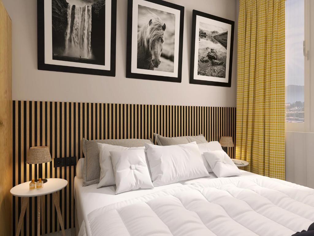 a bedroom with a large white bed with pictures on the wall at Hotel Etropol Center Etropole in Etropole