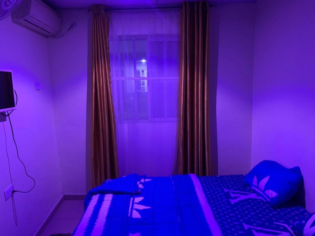fioletowy pokój z łóżkiem i oknem w obiekcie TSG Hotel w mieście Ado Ekiti