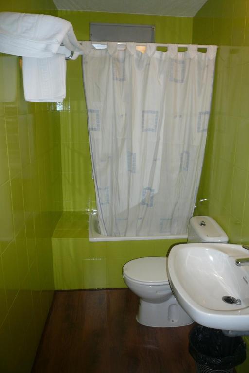 a green bathroom with a toilet and a sink at Hostal El Rincón - Casa Marcos in Yepes