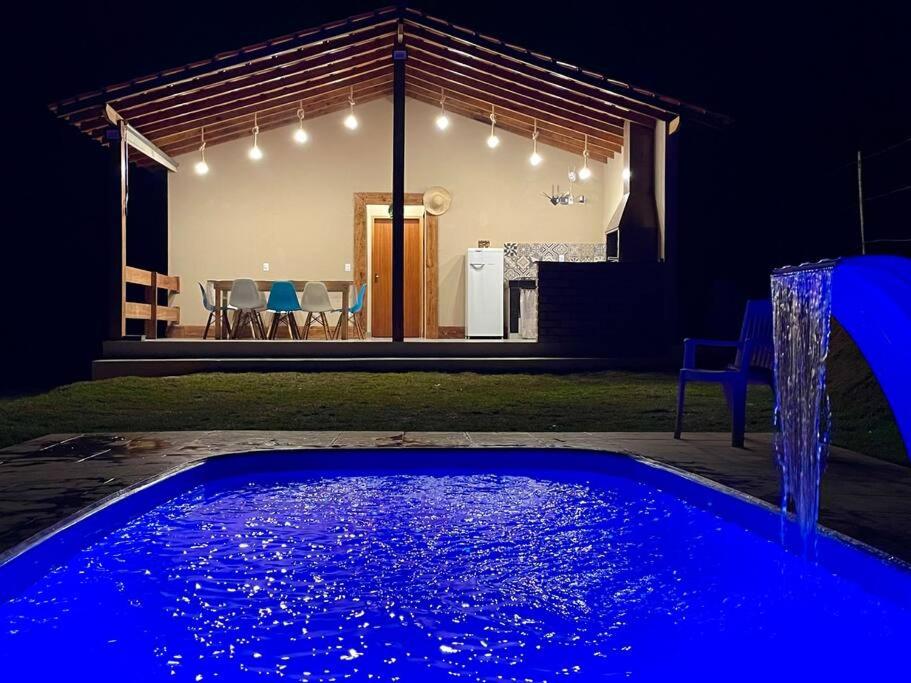 a swimming pool in front of a house at night at Chácara prox Rota do Vinho com piscina, churrasqueira, área verde, animaizinhos e muito sossego in São Roque
