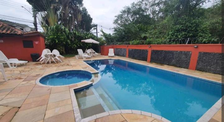 una piscina en un patio con sillas y una valla en Flat charmoso na praia de Juquehy, en São Sebastião