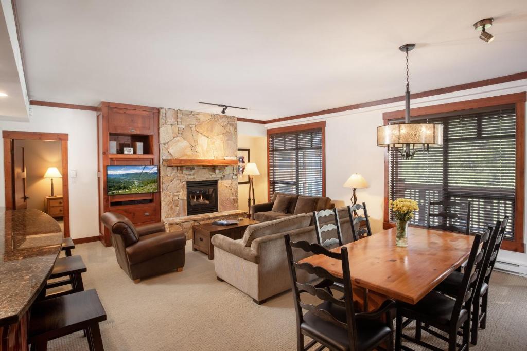 a living room with a table and a couch and a fireplace at First Tracks Lodge in Whistler