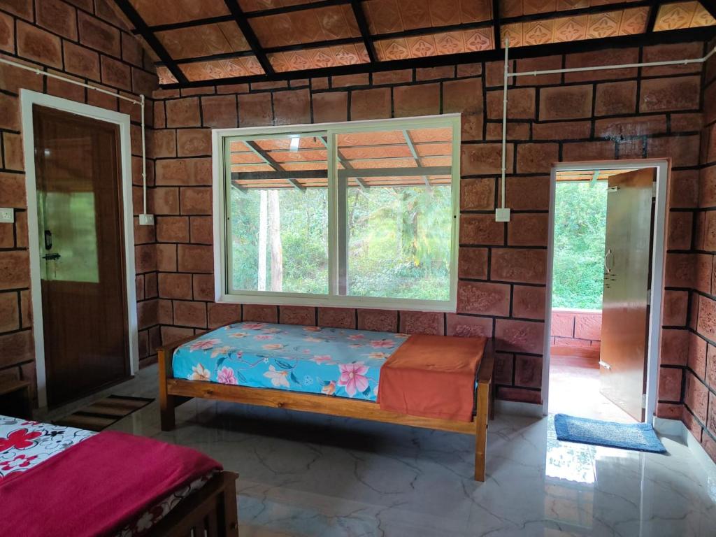 een kamer met een bed en een raam bij Nature Spot Cottages in Kurchi