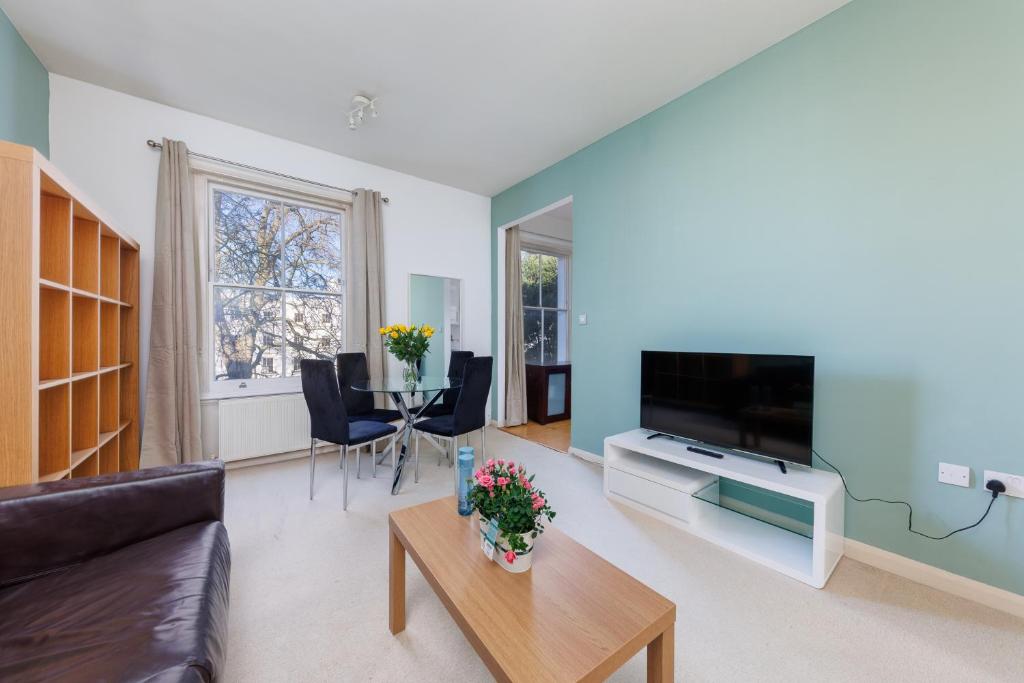 uma sala de estar com um sofá e uma televisão em Notting Hill Gem - Stylish 1 BR Apartment em Londres