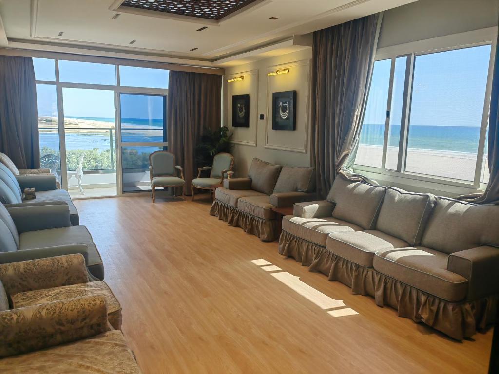 uma sala de estar com sofás e cadeiras e o oceano em الشقة البحرية الدهاريز em Salalah