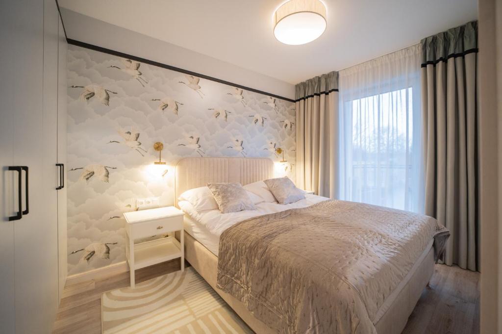 ein Schlafzimmer mit einem Bett und einer Wand mit Vogeltapete in der Unterkunft APARTAMENT Ceynowa in Karthaus