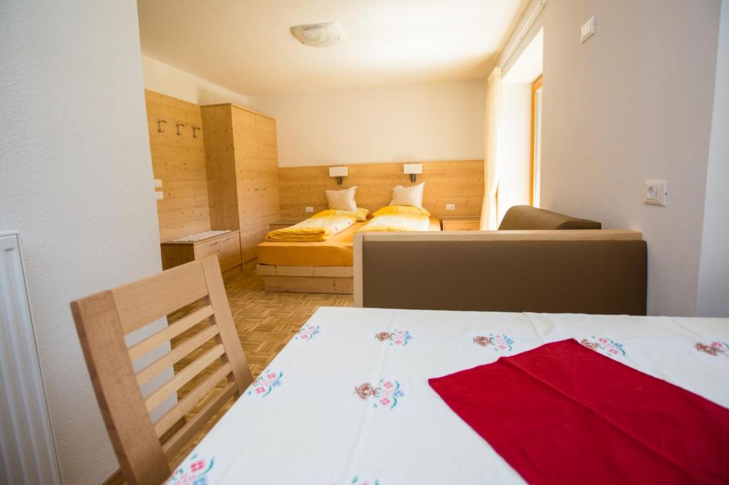 Habitación pequeña con 2 camas y mesa con toalla roja. en Appartamenti Genziana, en La Villa