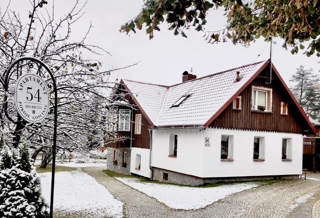 een huis bedekt met sneeuw met een bord ervoor bij Apartamenty Gościnne 54 in Szklarska Poręba