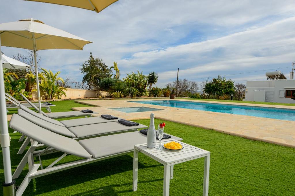 een stoel en een tafel met een parasol naast een zwembad bij New! Villa Can Blai in Santa Eularia des Riu