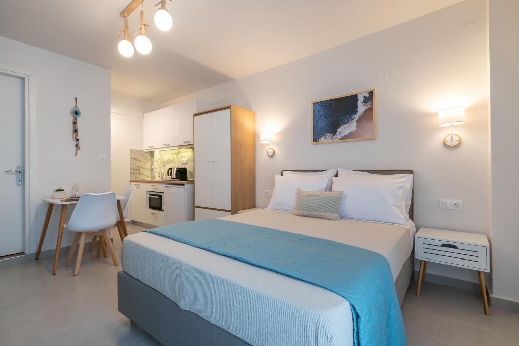 a bedroom with a large bed and a kitchen at ALMIRA Studios Limnos 2 in Mirina