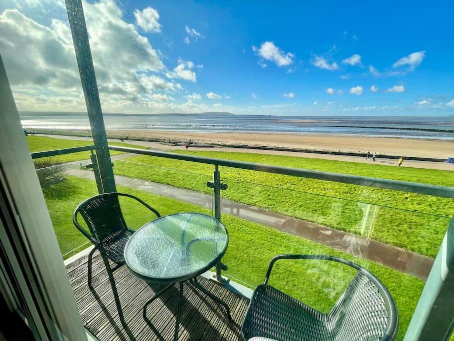 a balcony with a table and chairs and a beach at Beachfront Bliss with Spectacular Views in Llanelli