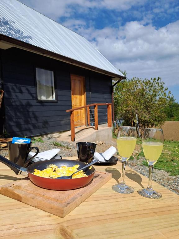 una mesa con un plato de comida y dos copas de vino en Refugio Golondrina en Futrono