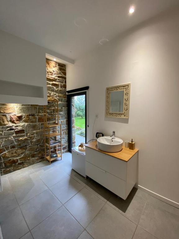 a bathroom with a sink and a stone wall at L'Hôtié de Brocéliande, au coeur des sites naturels et légendaires in Paimpont
