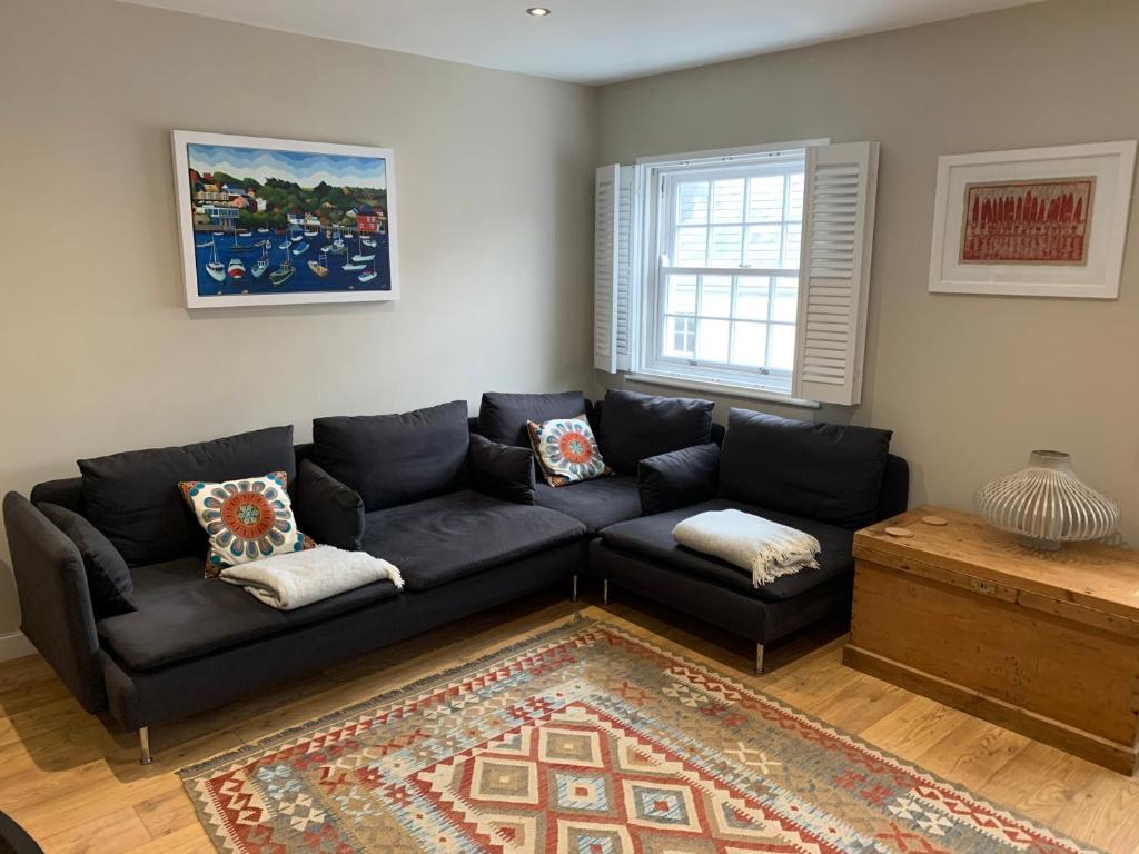 ein Wohnzimmer mit einem schwarzen Sofa und einem Fenster in der Unterkunft Lovely flat, balcony & woodstove, parking close in St. Agnes 