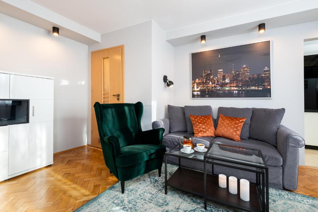 ein Wohnzimmer mit einem Sofa und einem Stuhl in der Unterkunft Apartament Spodek II - 100 m od Spodka - by Kairos Apartments in Kattowitz