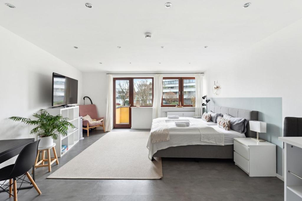 een witte slaapkamer met een bed en een bureau bij Salí Homes HZ42 Studio im Zentrum Bayreuths mit Balkon in Bayreuth