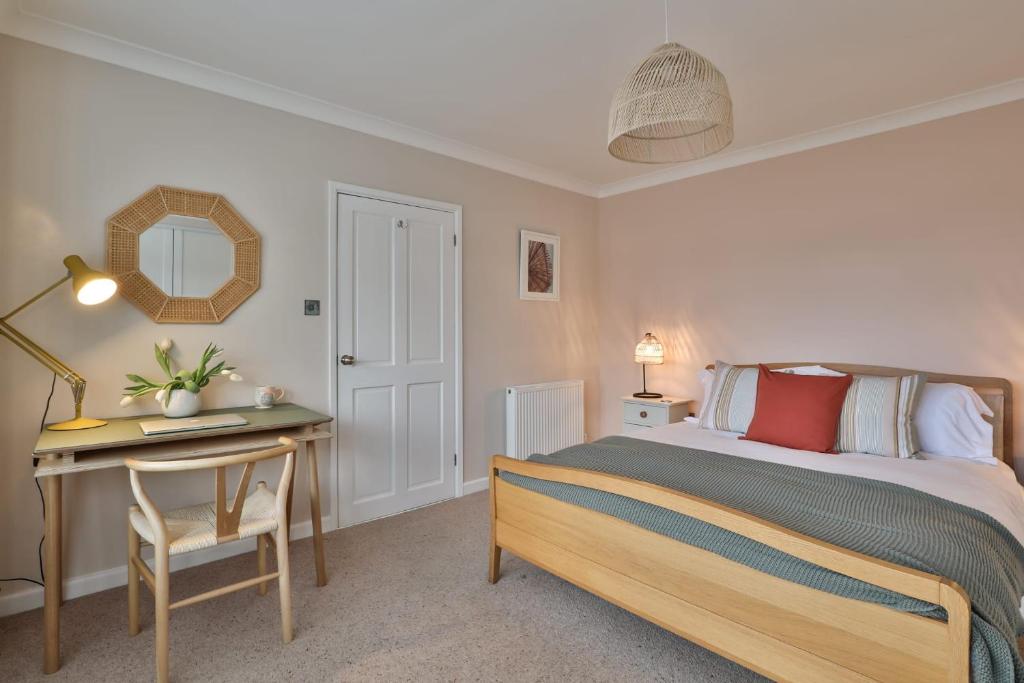 1 dormitorio con cama, escritorio y espejo en Cloudbreak Braunton North Devon en Braunton