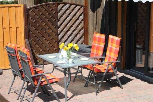 un patio con mesa y 4 sillas en Ferienhaus Caro, en Federow
