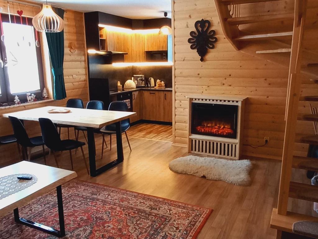 a living room with a table and a fireplace at Domek na Hubce II in Maniowy