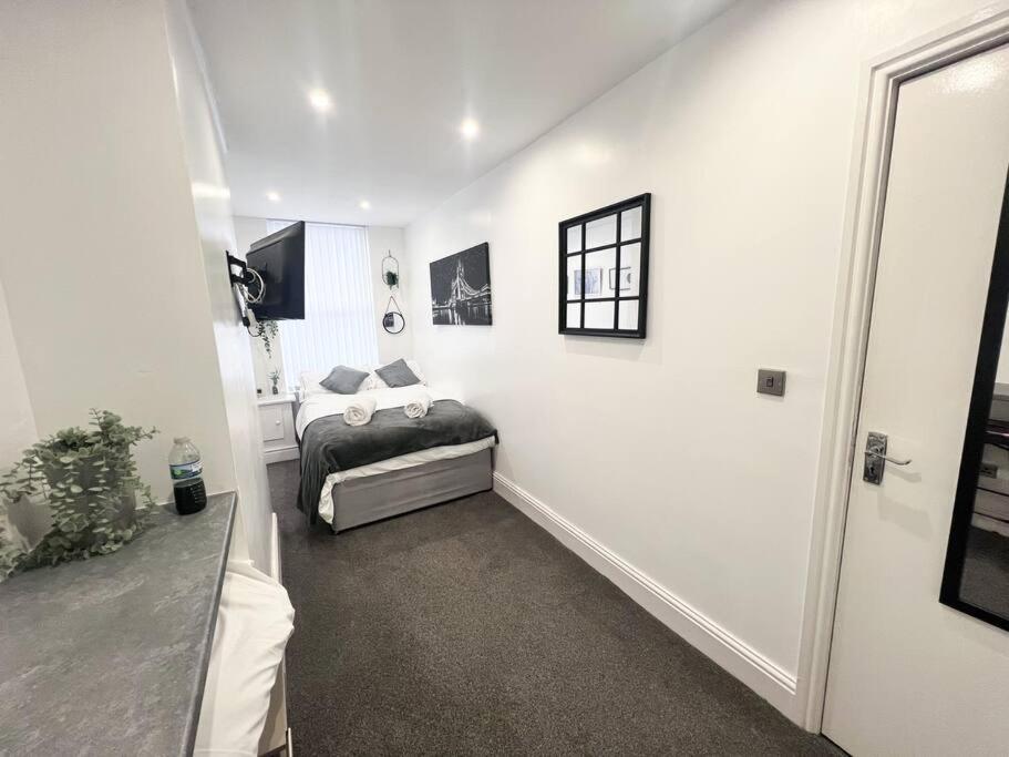 ein Schlafzimmer mit einem Bett in einem weißen Zimmer in der Unterkunft Cosy Flat by Anfield: 5 Minutes from the Stadium! in Liverpool