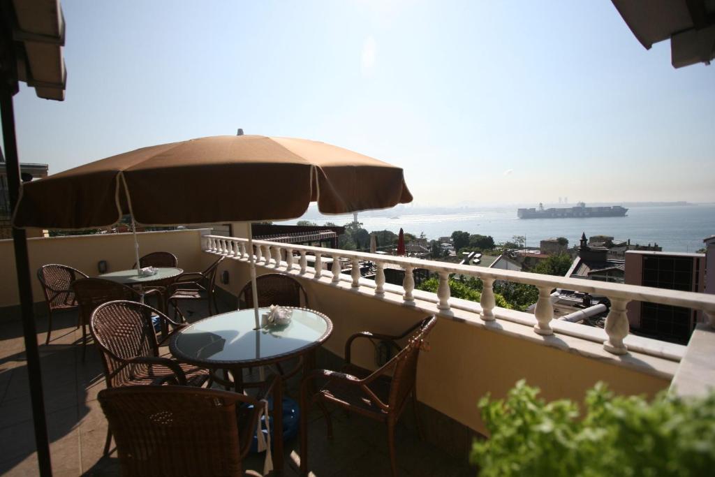 einen Balkon mit Tischen, Stühlen und einem Sonnenschirm in der Unterkunft Hanedan Hotel in Istanbul