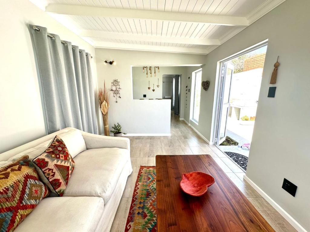 a living room with a white couch and a wooden table at Brunia Bay Apartment in Hermanus