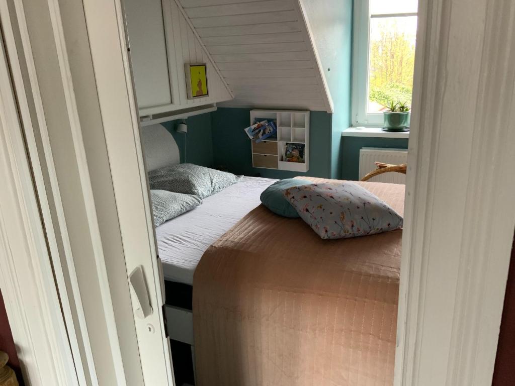 ein kleines Bett in einem kleinen Zimmer mit Fenster in der Unterkunft Spiced Bed&Breakfast in Nykøbing Falster