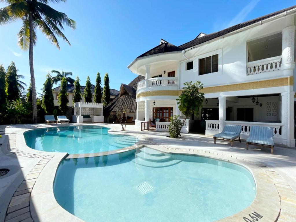 a swimming pool in front of a house at Tahira Villa in Diani Beach
