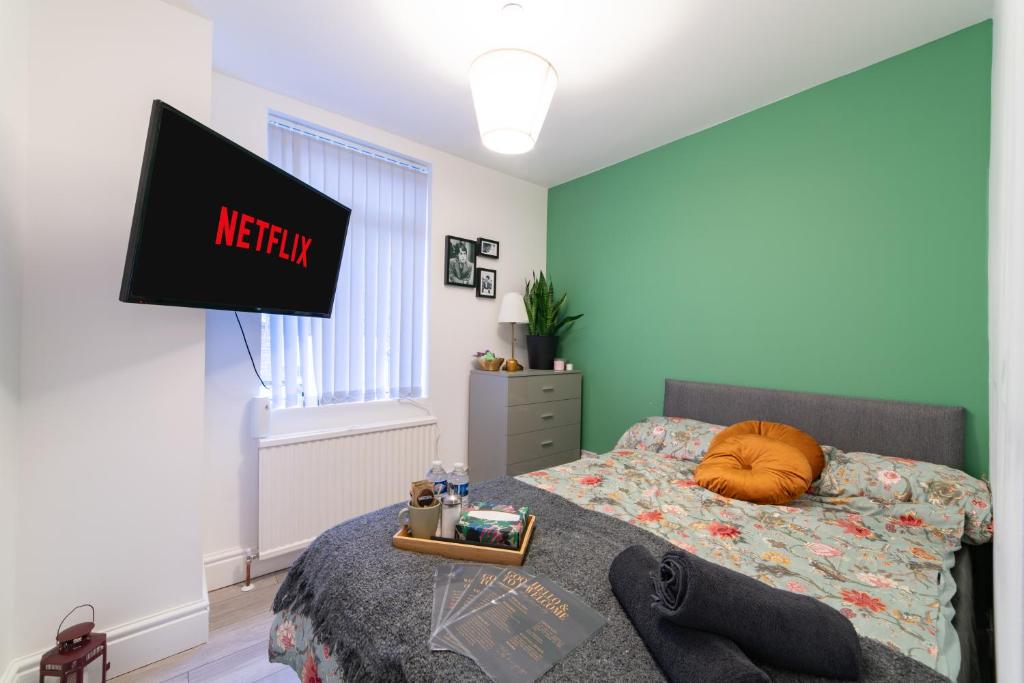 a bedroom with a bed and a tv on the wall at Rooms with Netflix in a shared accommodation, 10 min walk from the stadium in Liverpool