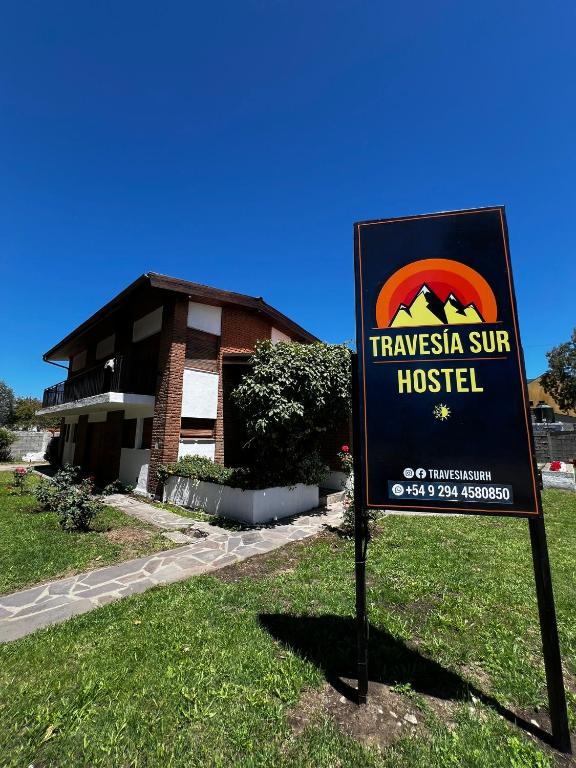 a sign in the grass in front of a building at Travesia Sur Hostel in El Bolsón