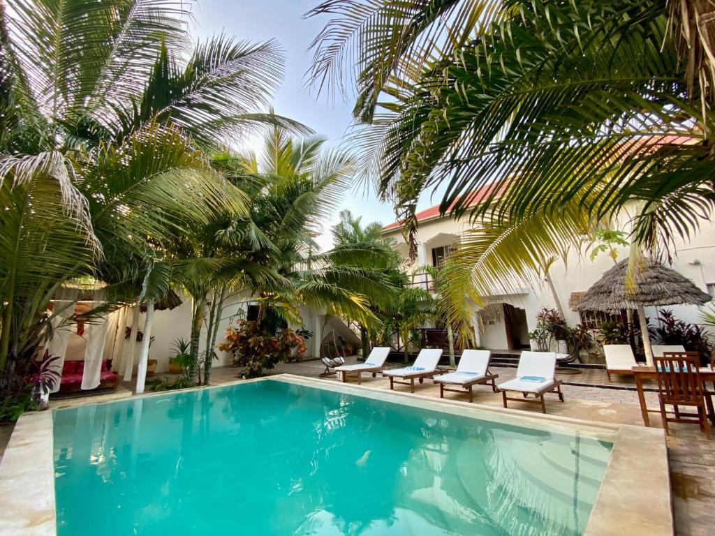 una piscina con sillas y palmeras en CeZeRe THE PALM HOTEL en Paje