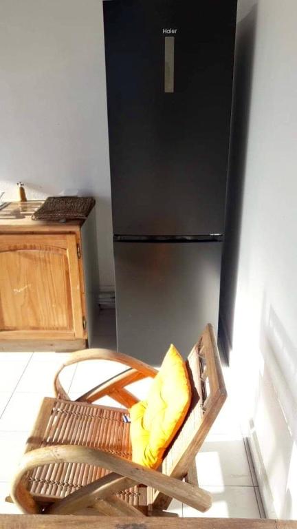a chair with a yellow pillow in a kitchen with a refrigerator at Appartement d&#39;une chambre avec terrasse amenagee a Grand Bourg in Grand-Bourg