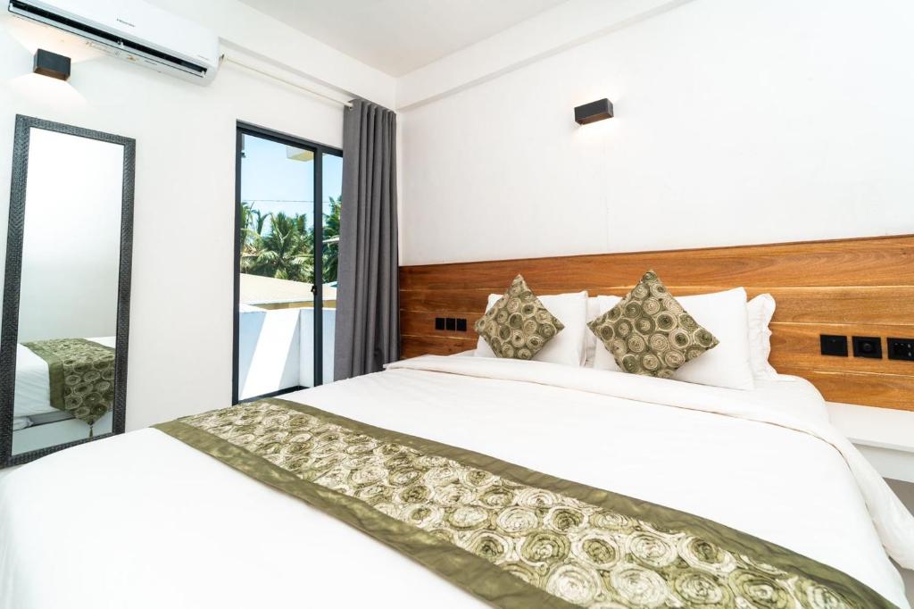 1 dormitorio con cama blanca y balcón en The Shark Residence, en Fuvahmulah