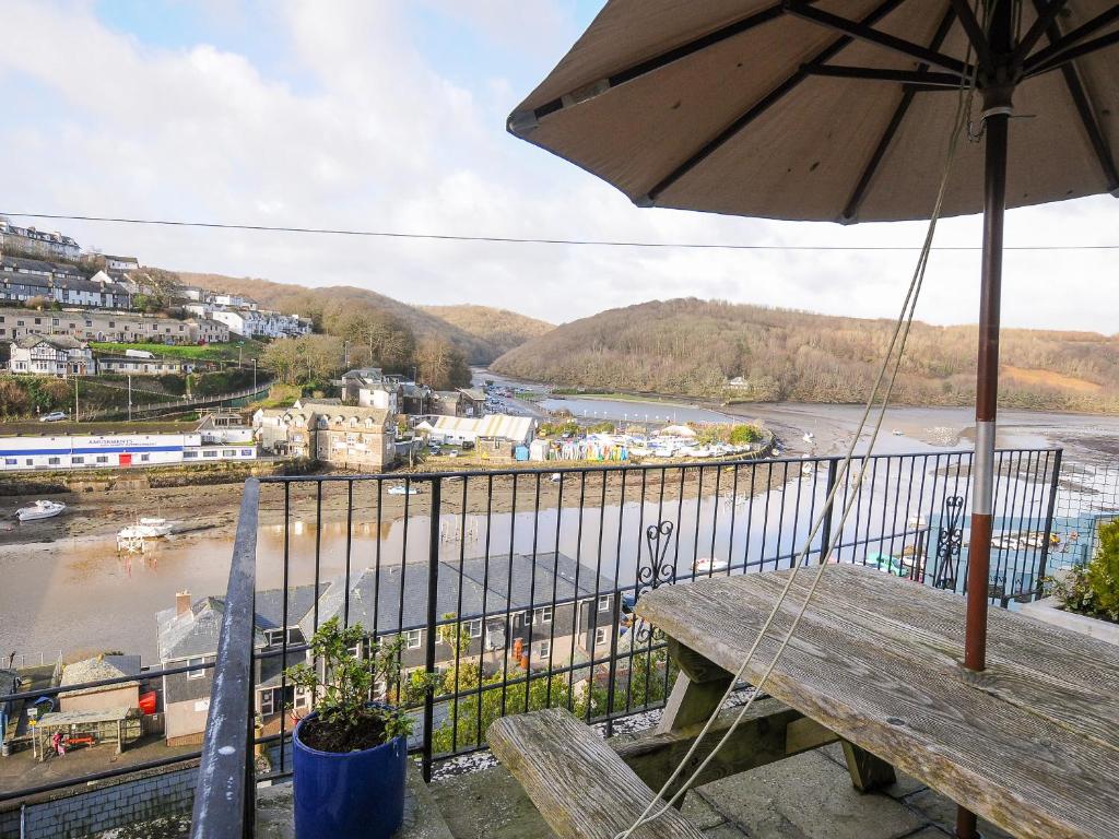 a balcony with a table and an umbrella and a river at Elmbank in Looe