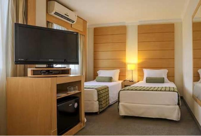 a hotel room with two beds and a flat screen tv at Suite dupla ao lado do aeroporto de Congonhas in Sao Paulo