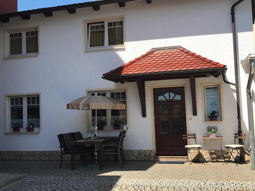 een wit huis met een tafel en een paraplu bij Ferienwohnung Plötner in Bad Klosterlausnitz