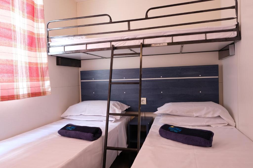 two beds in a room with a bunk bed at Happy Camp mobilehomes in Camping Apollonia in Plakias