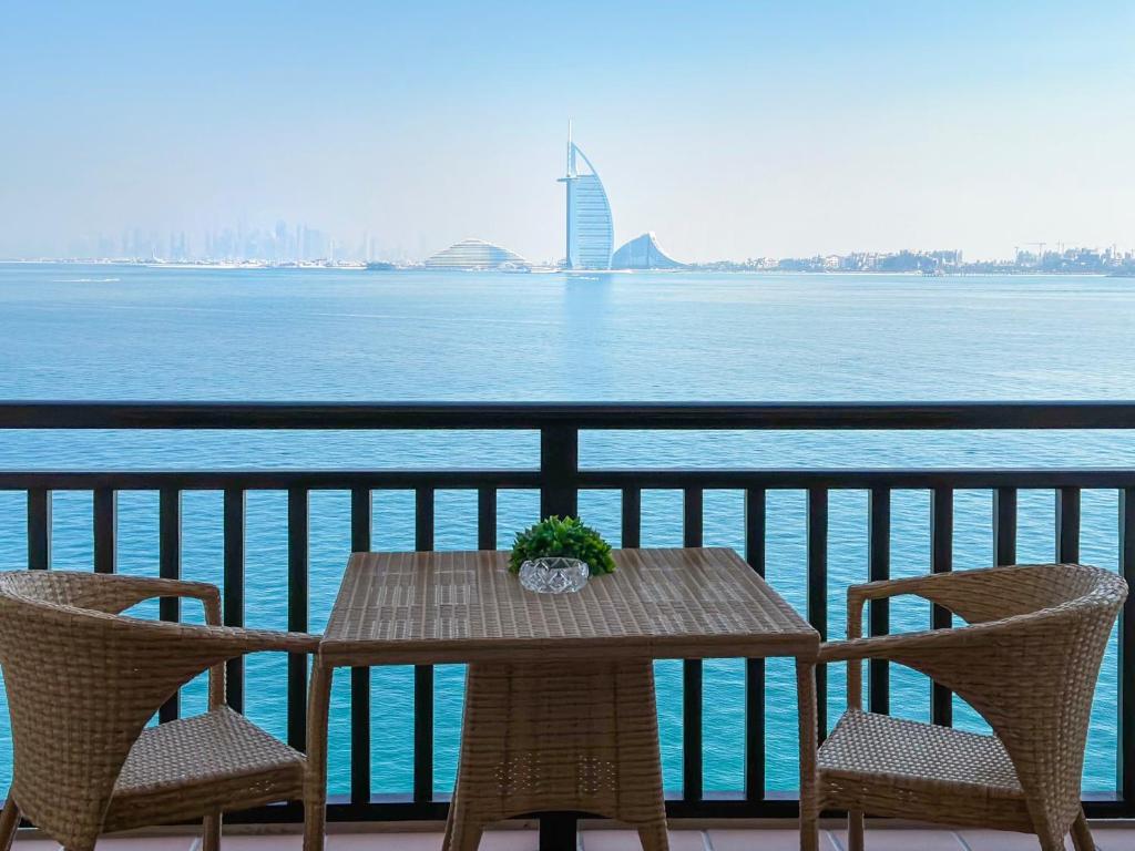 a table and chairs on a balcony overlooking the water at Direct Burj Al Arab View 1BR Nirvana at 5 Star Resort in Dubai
