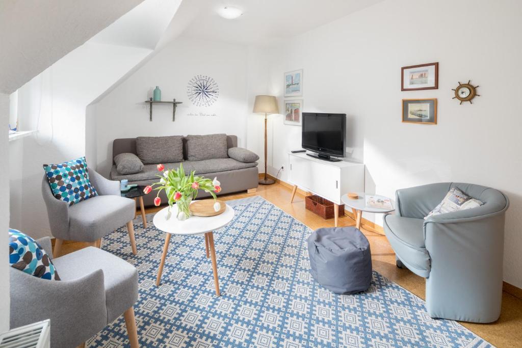 een woonkamer met een bank en stoelen en een tv bij Himmelsrichtung in Norderney
