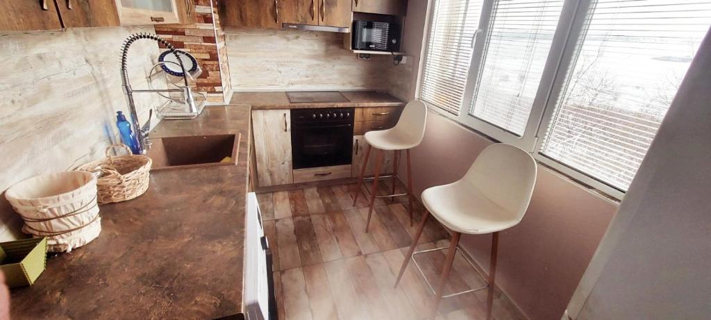eine Küche mit zwei weißen Stühlen und einer Arbeitsplatte in der Unterkunft Апартамент Холидей in Razgrad