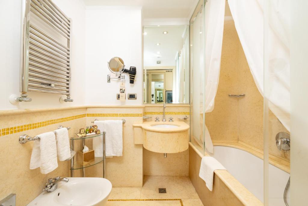 a bathroom with a sink and a toilet and a tub at Hotel A La Commedia in Venice