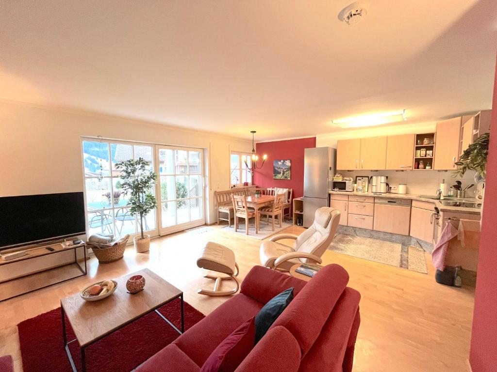 uma sala de estar com um sofá vermelho e uma cozinha em Ferienwohnung Bergnest em Bad Hindelang