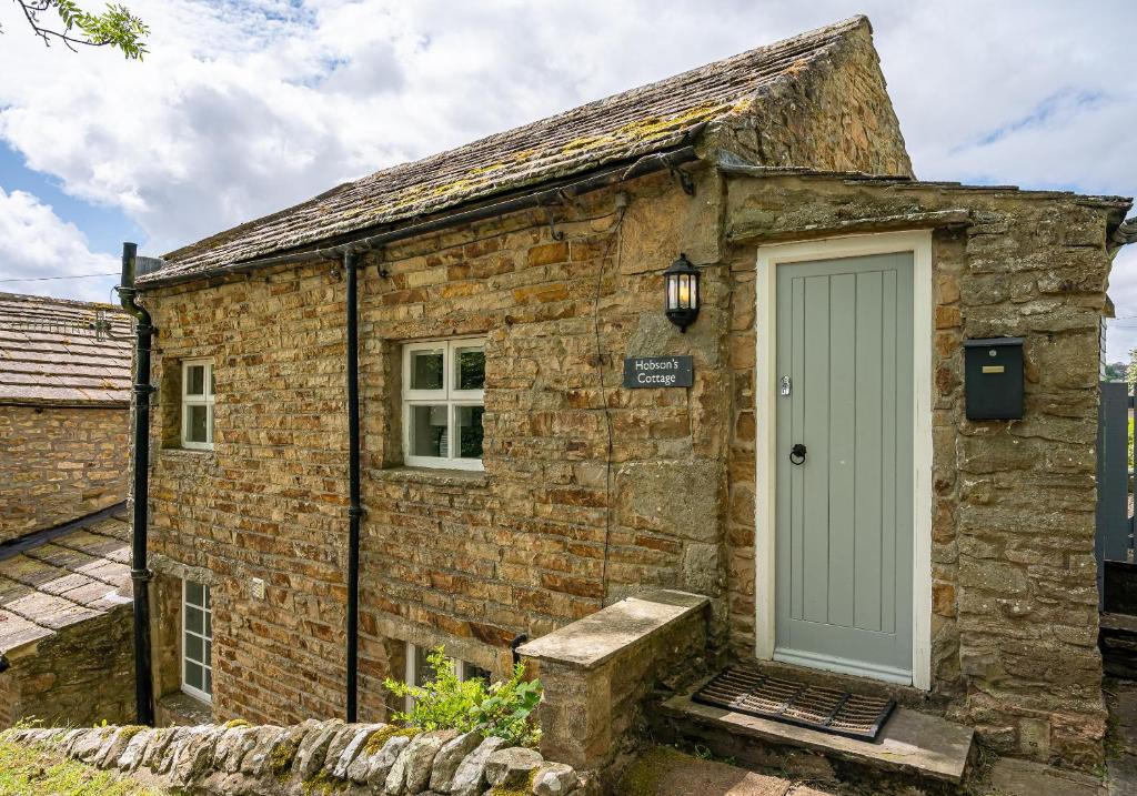 a stone cottage with a green door on the side at Hobsons Cottage in Grinton