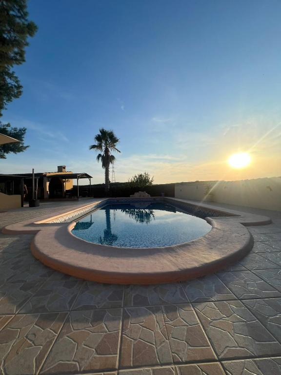 a pool in a patio with a sunset in the background at The Olive Mill in La Murada