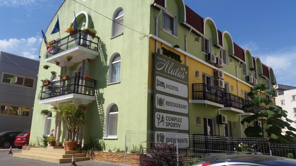 un bâtiment vert et jaune avec des personnes sur les balcons dans l'établissement COMPLEX Alutus -Camere de inchiriat, à Mangalia