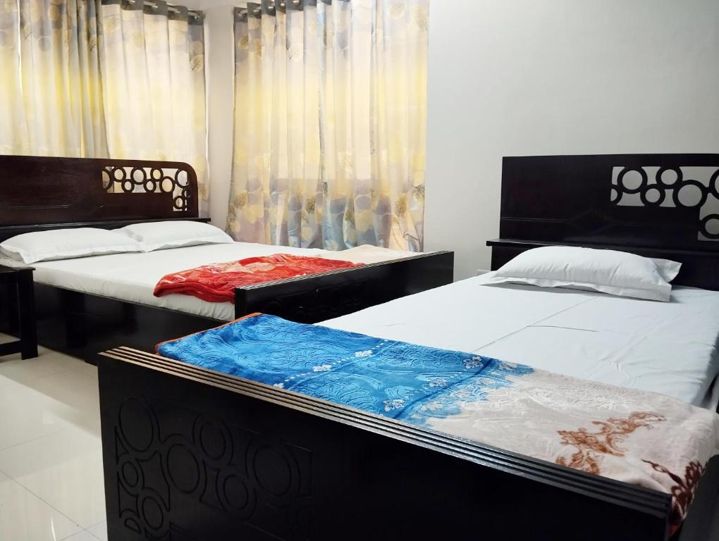 two beds sitting next to each other in a bedroom at Hotel Labbaik Dhanmondi in Dhaka