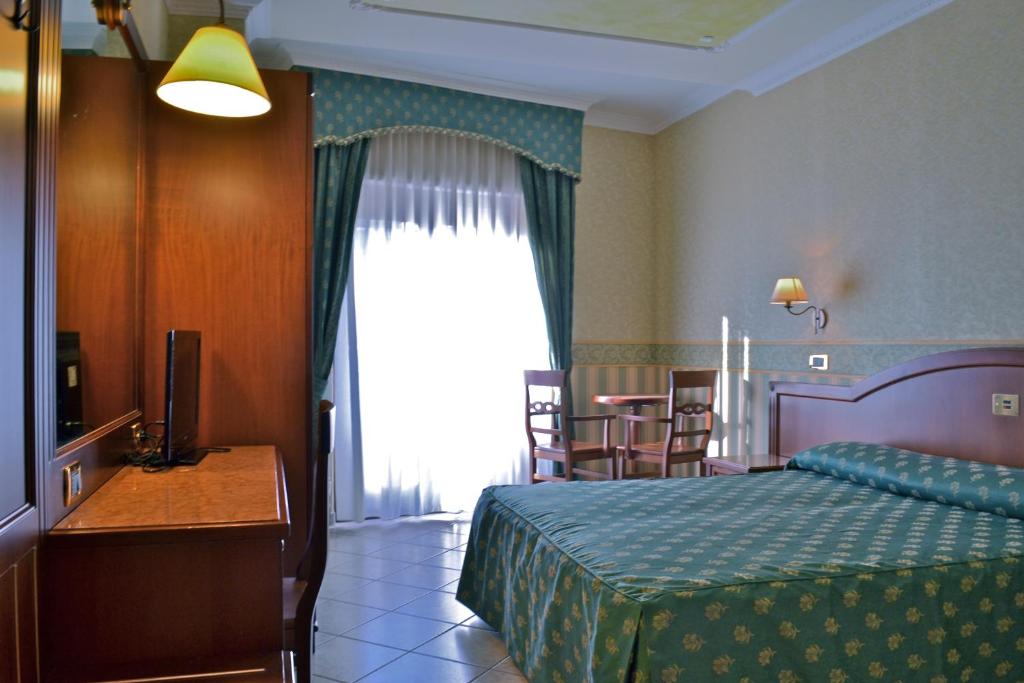 a bedroom with a bed and a table and a window at Hotel Valle Rossa in San Giovanni Rotondo