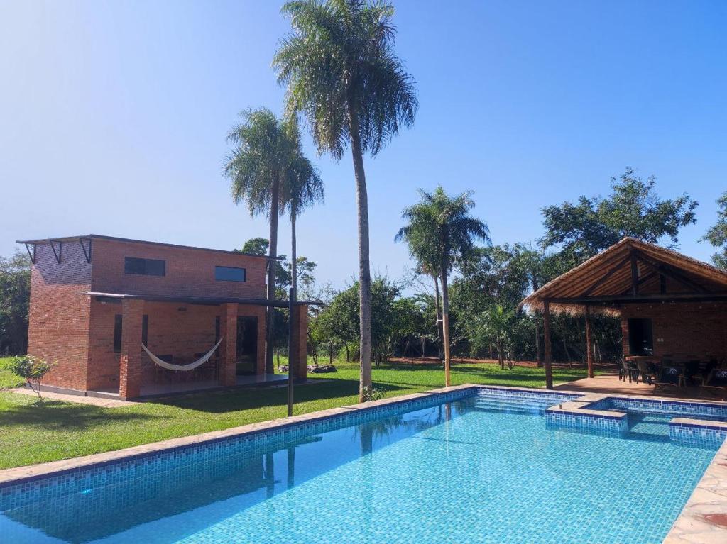 a swimming pool in front of a house with palm trees at Palm Village in Nueva Italia