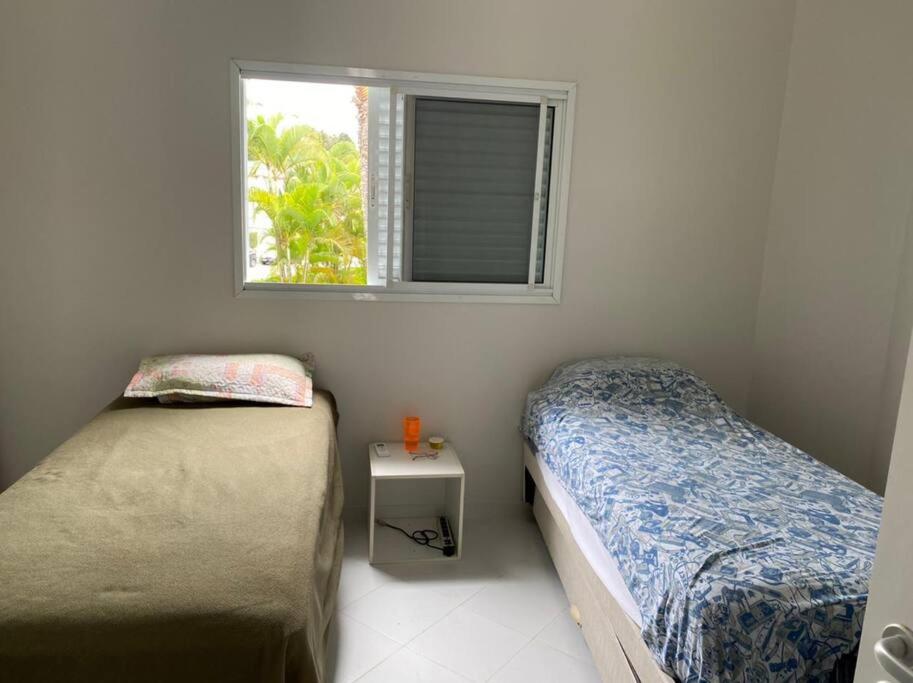 Duas camas num pequeno quarto com uma janela em Casa em Riviera de São Lourenço Prática e Confortável, Reformada e Equipada! em Bertioga