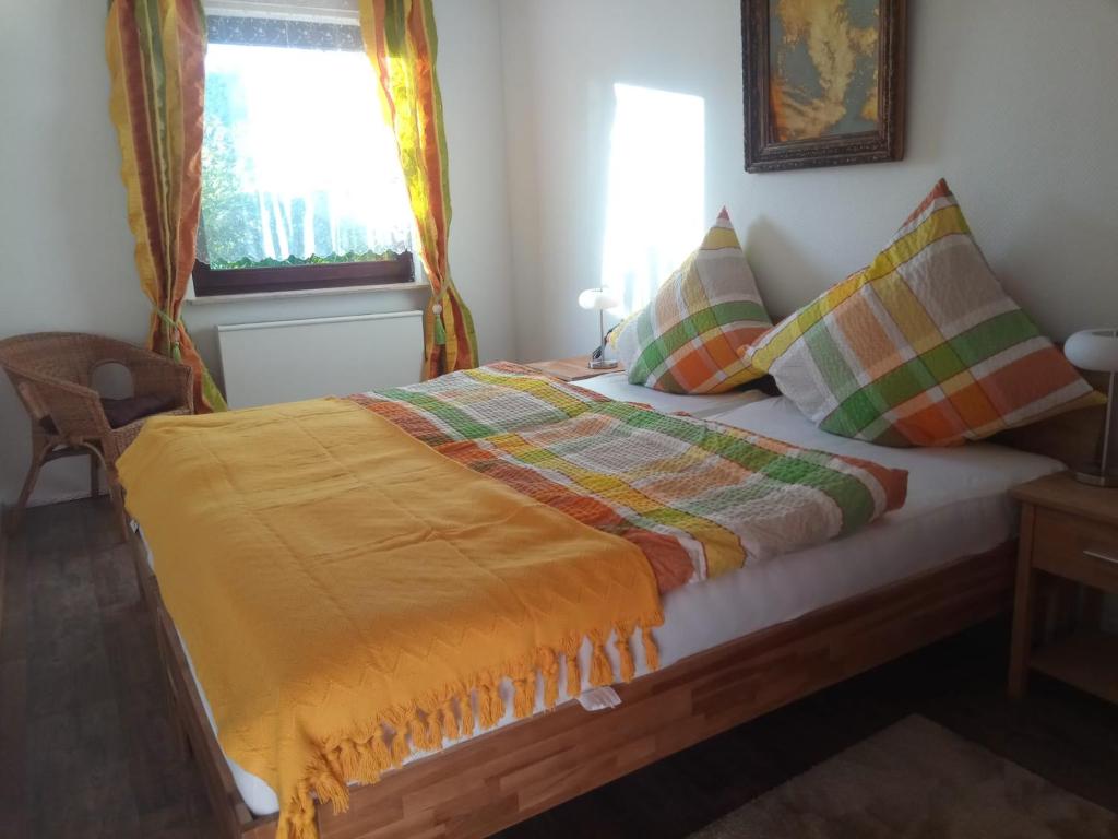 a bedroom with a bed with a yellow blanket on it at Haus am Römerstich in Auen